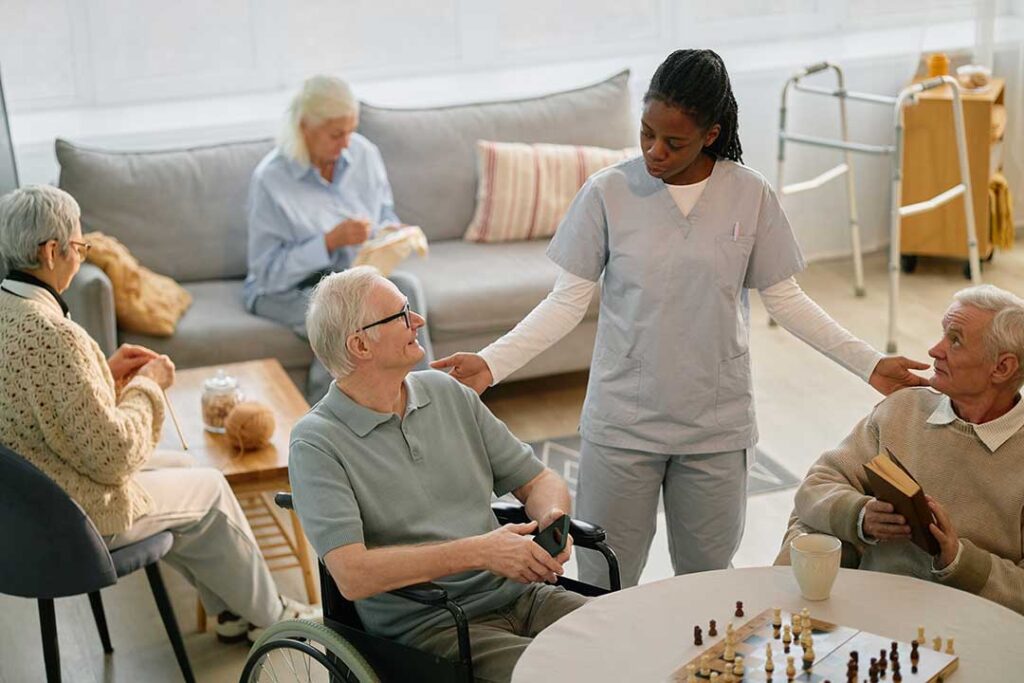 A small group of older adults socializing around a table with healthy snacks and drinks.