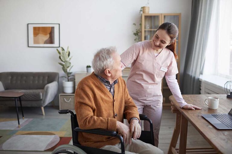 A family member and an older adult sit together in a comfortable common room, sharing conversation and smiles.
